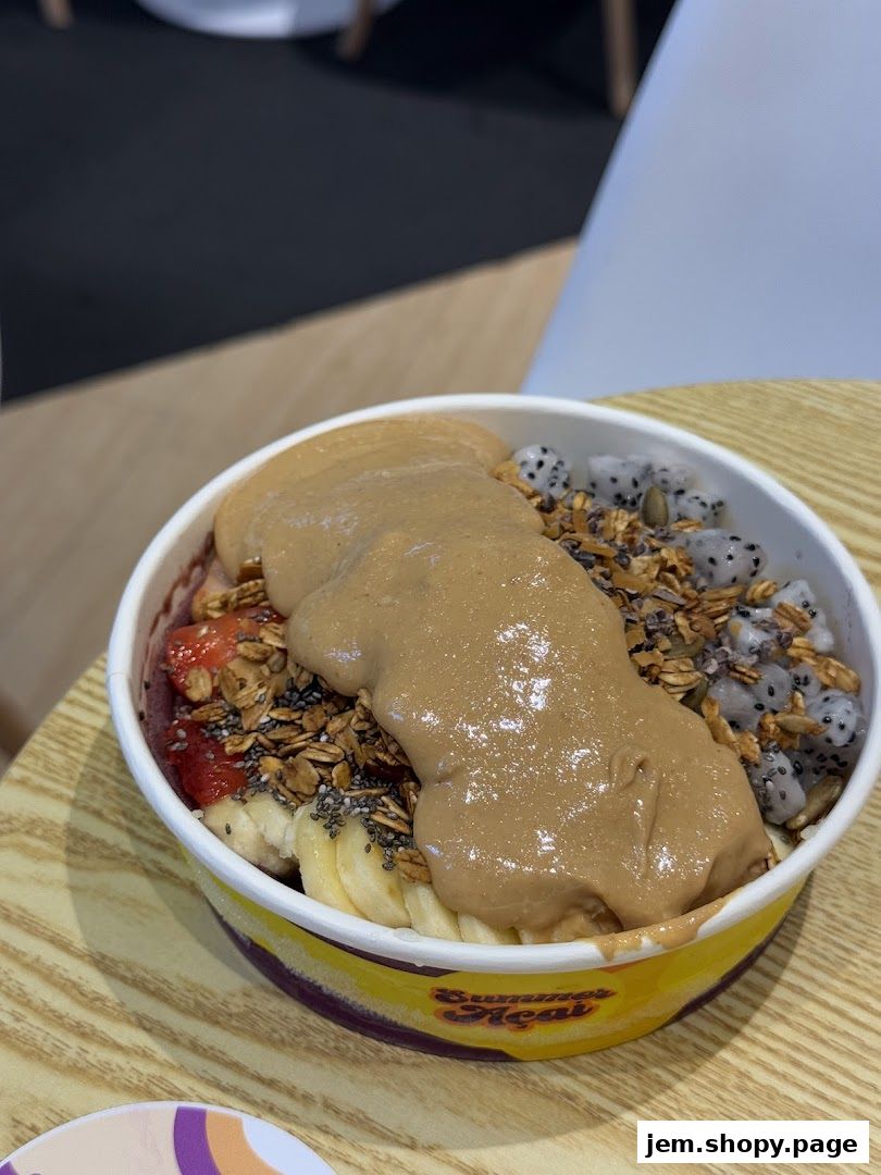 A delicious açaí bowl topped with peanut butter, granola, fruits, and seeds.