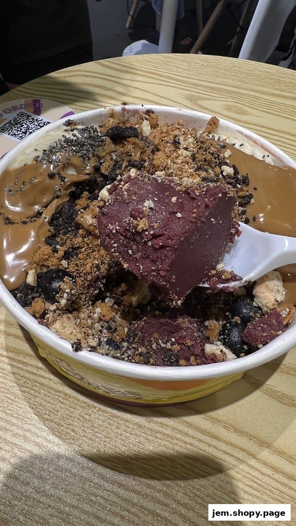 A close-up of a delicious açaí bowl topped with fruits, nuts, and sauces.