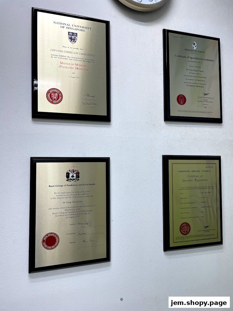Framed medical certificates and accreditations displayed on a white wall.
