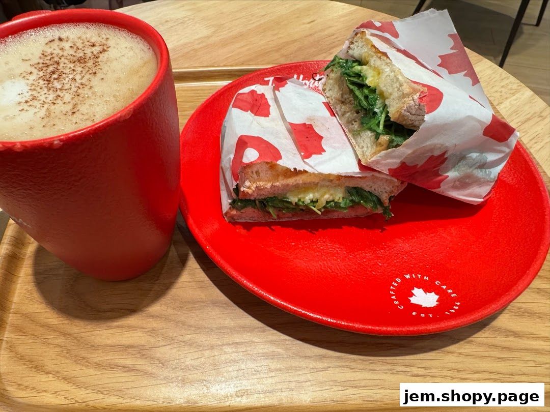 A red mug of coffee and a sandwich on a red plate with Canadian maple leaf branding.