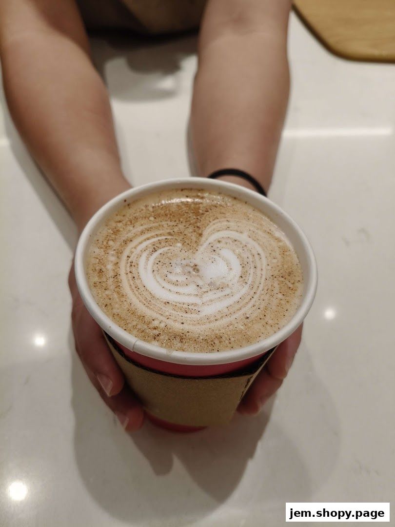 Hands holding a beautifully crafted latte with heart-shaped foam art.