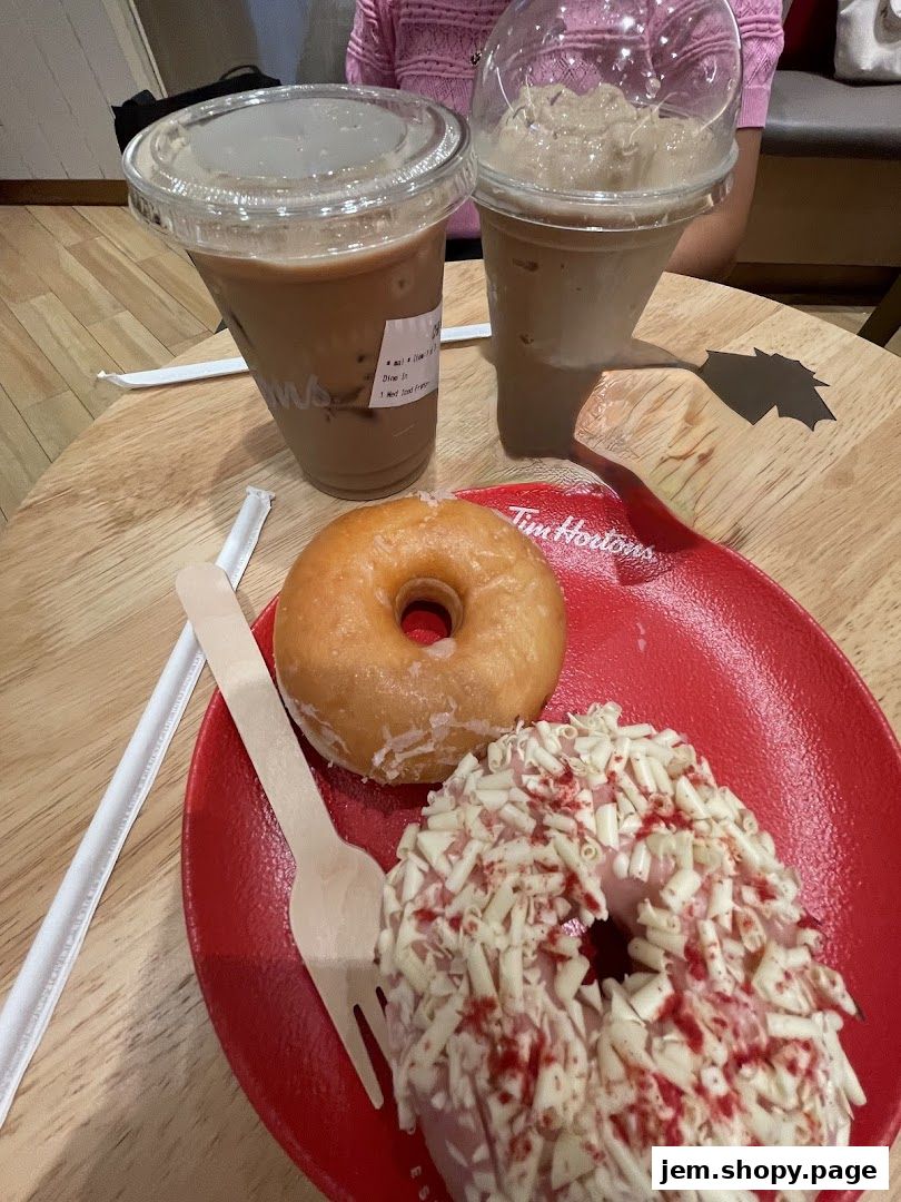 Two iced beverages and two donuts on a red plate with a wooden fork.