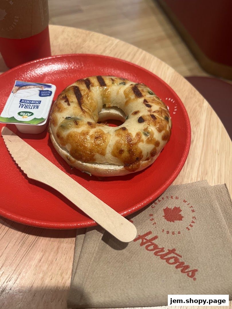A grilled bagel with cream cheese and a coffee cup from Tim Hortons.