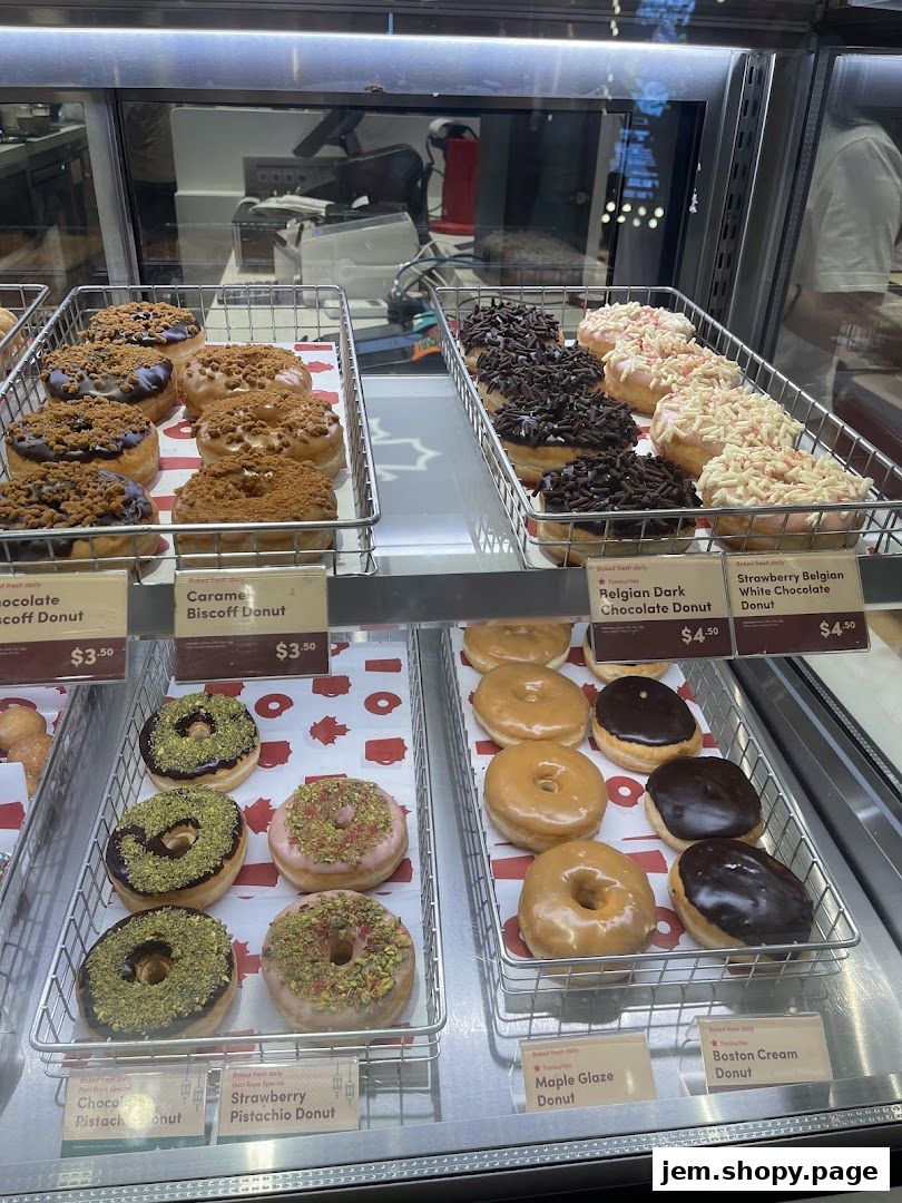 A display case filled with various donuts, including chocolate, caramel, pistachio, and glazed varieties.