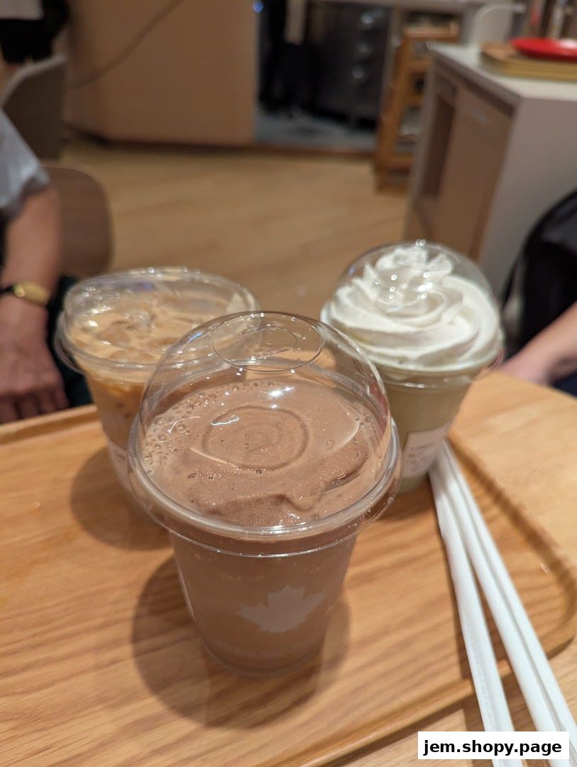 Three iced beverages, including a chocolate shake and a whipped cream topped drink, on a wooden tray.