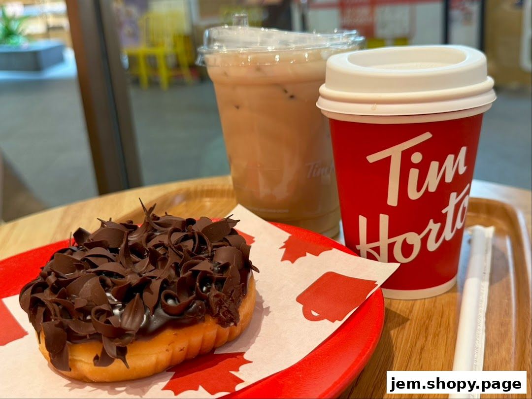 A chocolate-covered donut with chocolate shavings and a coffee drink on a tray.