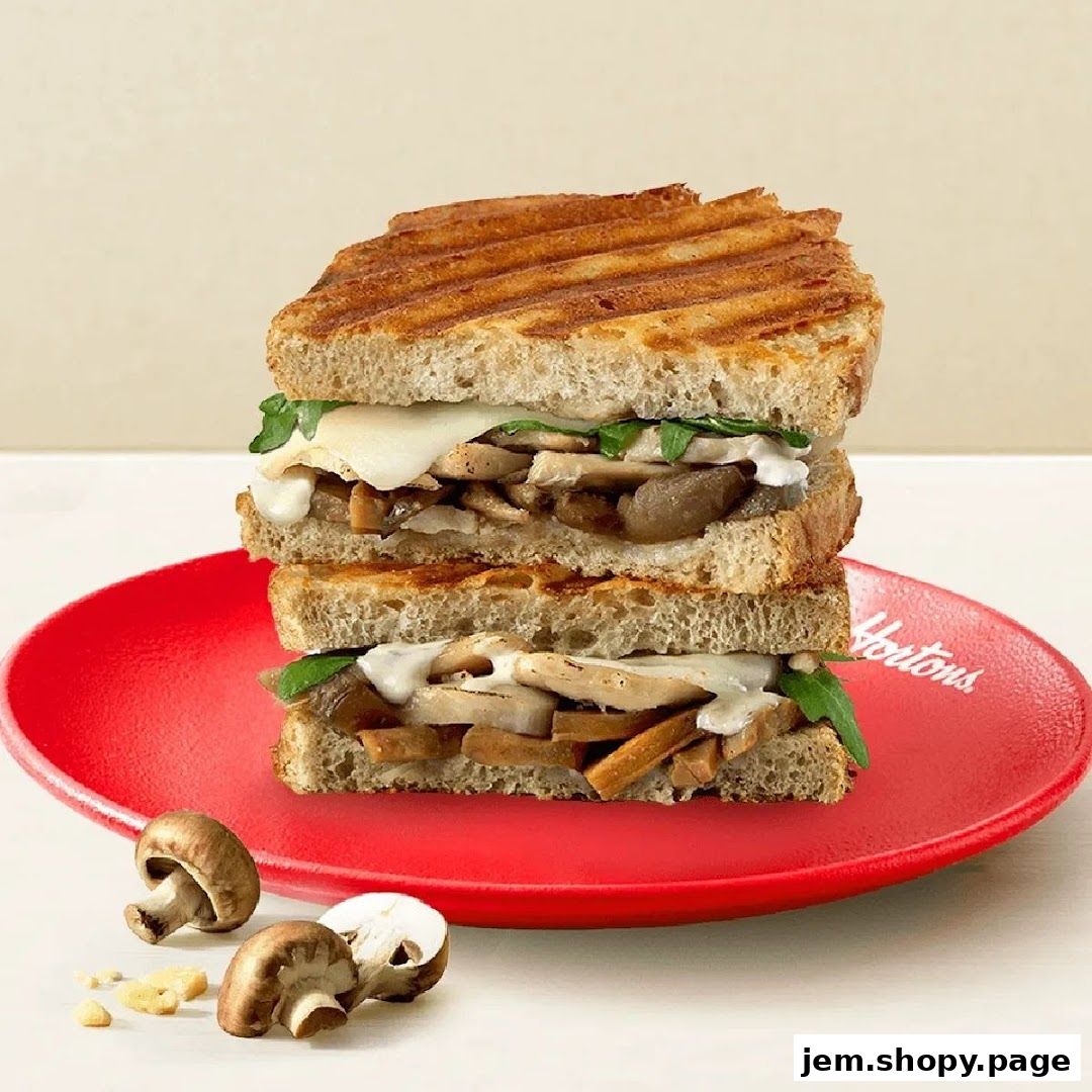 A stacked mushroom and chicken sandwich on a red plate with mushrooms and cheese.