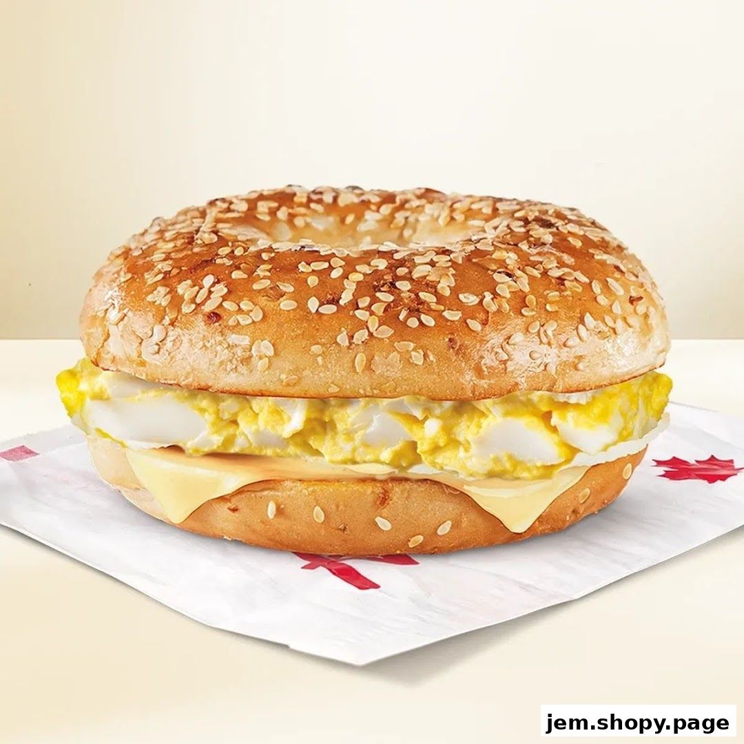 A close-up shot of a sesame seed bagel sandwich with scrambled eggs and cheese.