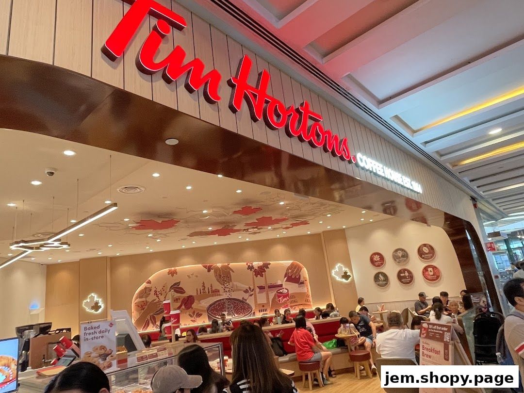 The exterior of a Tim Hortons coffee shop with customers inside and a prominent sign.