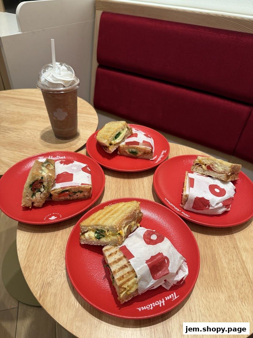 A selection of grilled sandwiches and a frozen beverage with whipped cream on a wooden table.