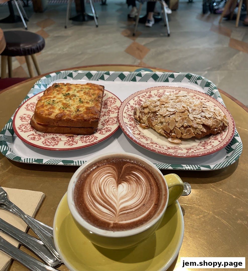 A tray with a savory toast, almond croissant, and a latte with heart art.