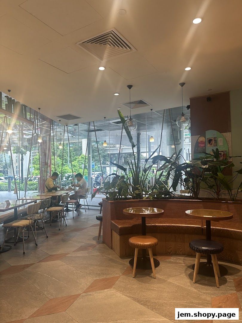 Interior view of Tiong Bahru Bakery with seating, plants, and natural light.