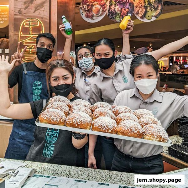 Bakery staff proudly present a tray of freshly baked pastries.