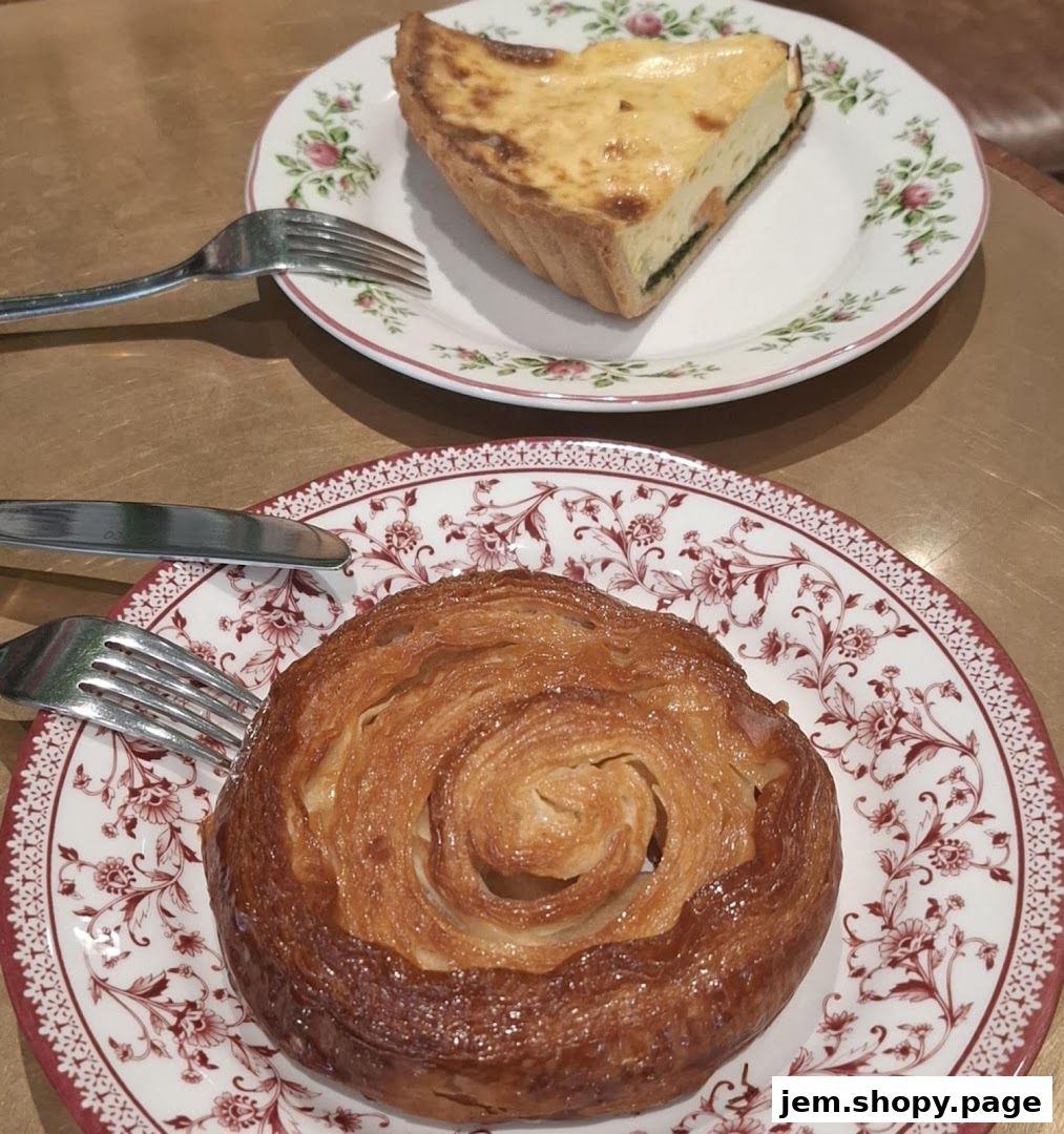 A flaky pastry and a slice of quiche served on decorative plates with cutlery.