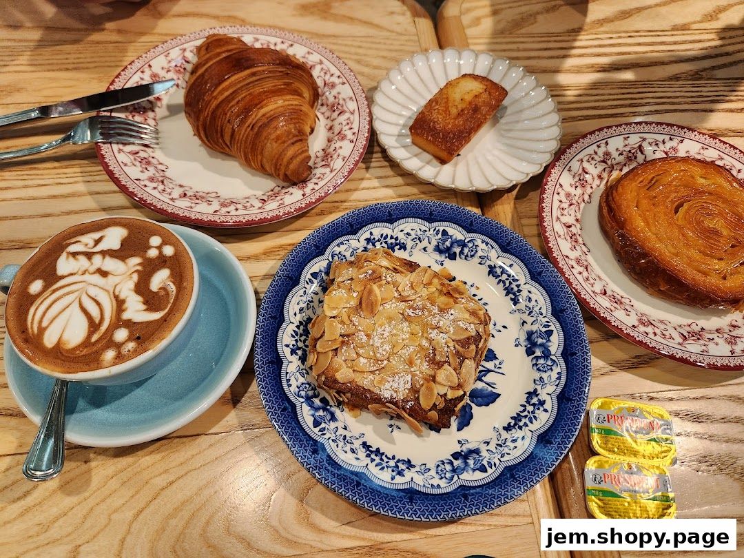 A delightful spread of pastries and coffee, featuring a croissant, almond pastry, and latte art.