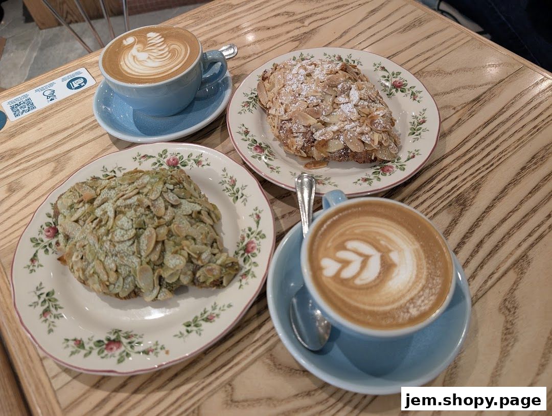 Two almond croissants and two lattes with latte art on a wooden table.