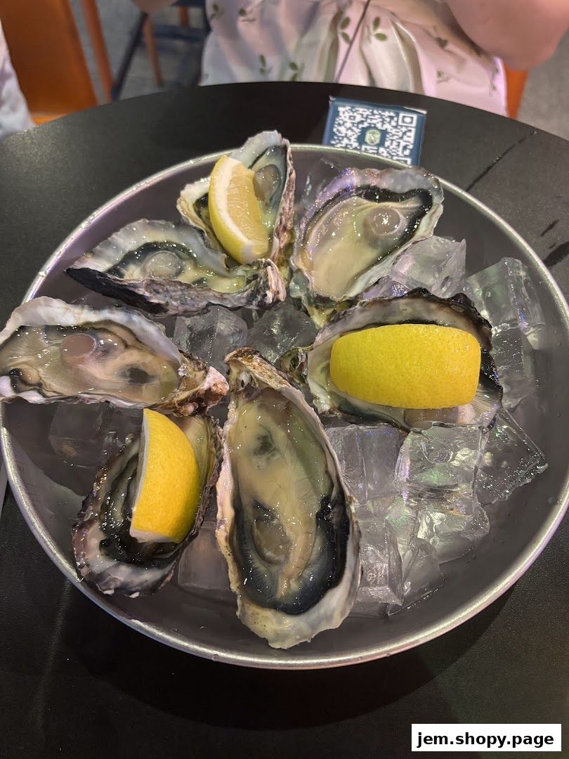 A platter of fresh oysters served on ice with lemon wedges.