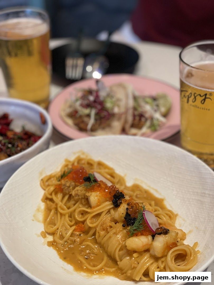 A close-up of a pasta dish with seafood, served with beer and tacos.