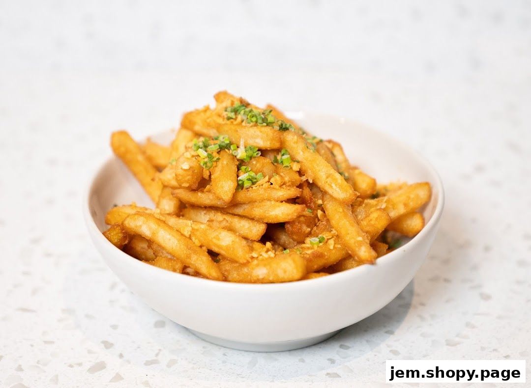 A white bowl filled with crispy golden fries, topped with chopped green onions and garlic.