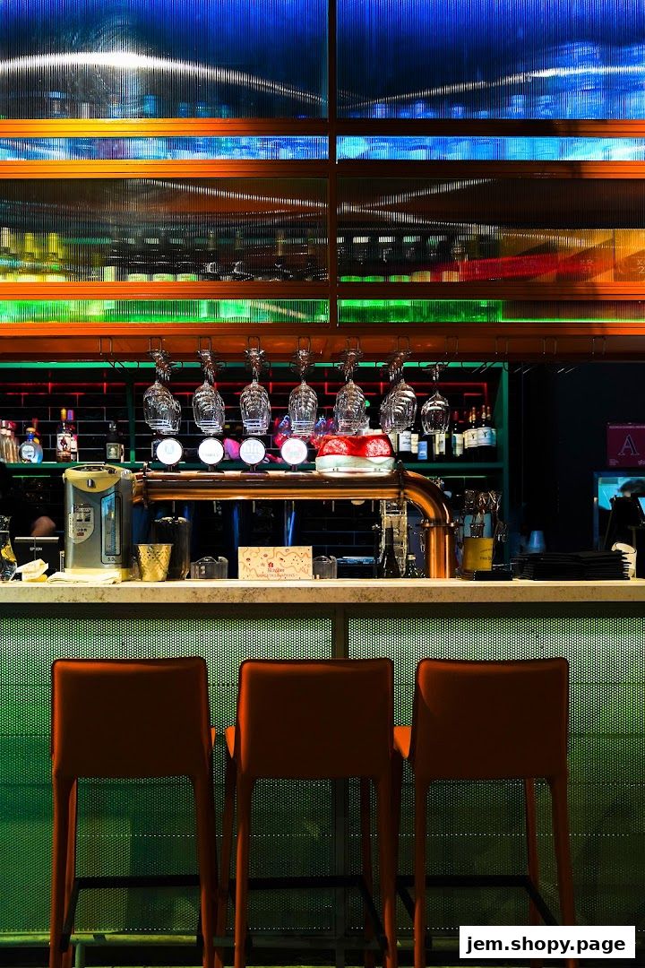 A modern bar with orange stools, beer taps, and colorful illuminated shelving.