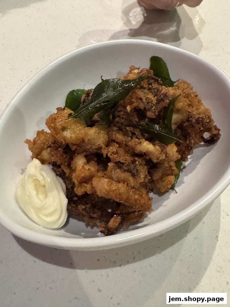 A white bowl filled with crispy fried calamari and a dollop of mayonnaise.