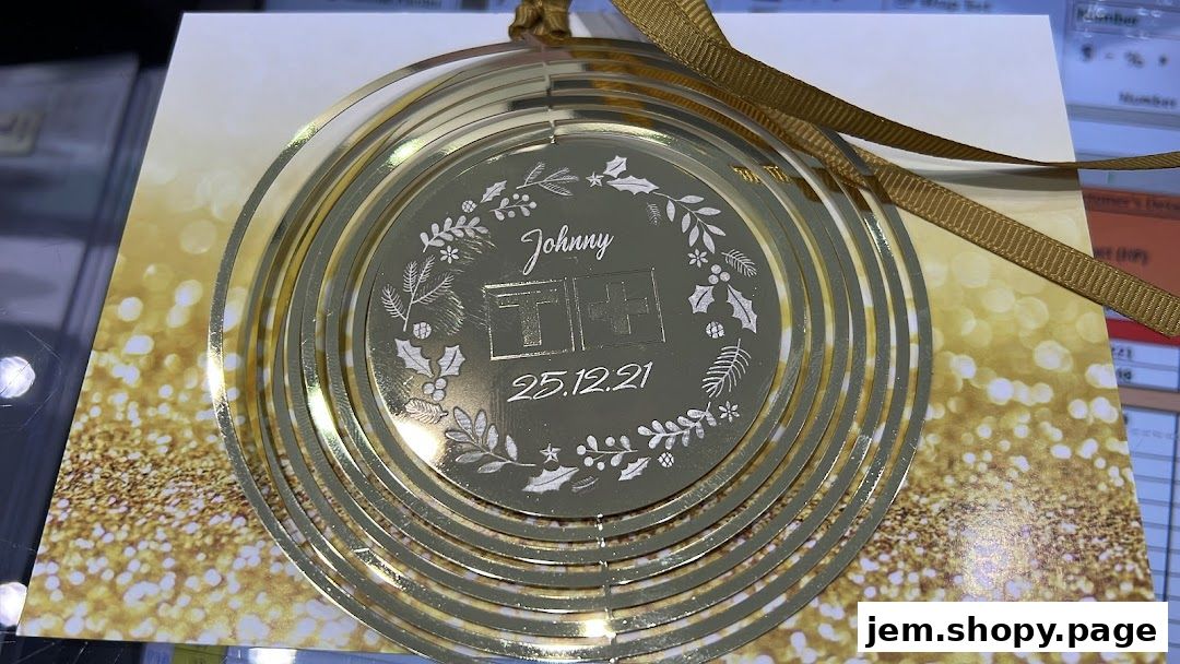A gold-colored Tissot branded ornament with a festive design and ribbon.