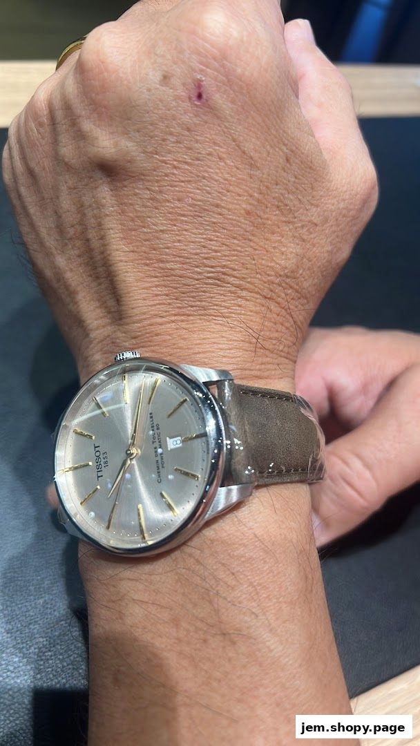 A close-up shot of a Tissot watch with a leather strap on a person's wrist.
