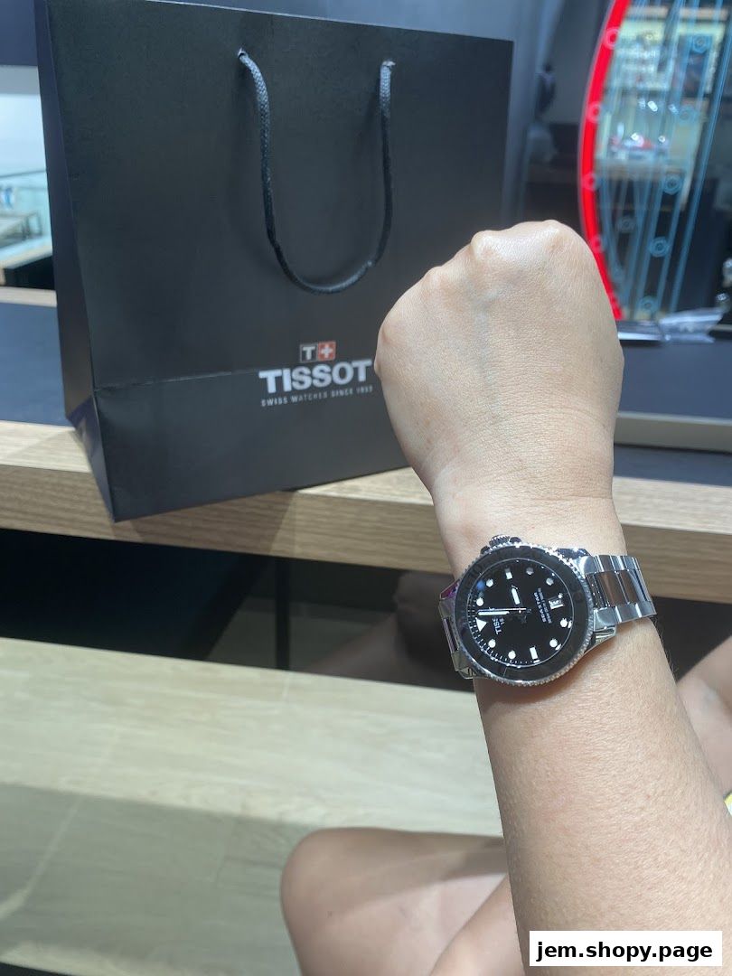 A person wearing a Tissot watch with a Tissot shopping bag in the background.