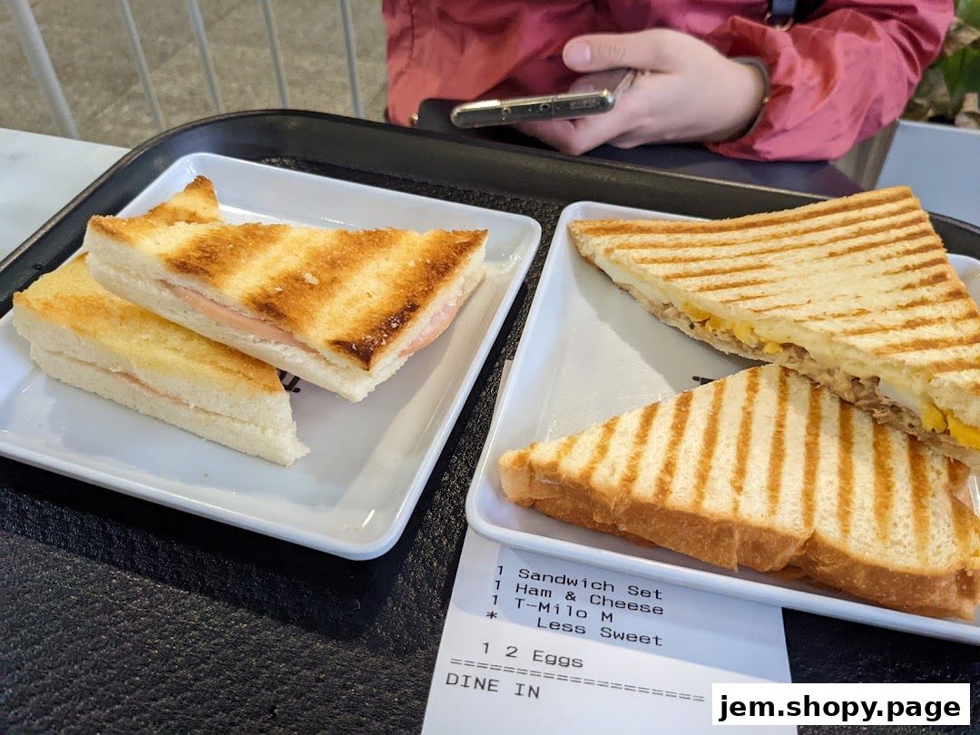 Two plates of toasted sandwiches and a receipt on a tray.