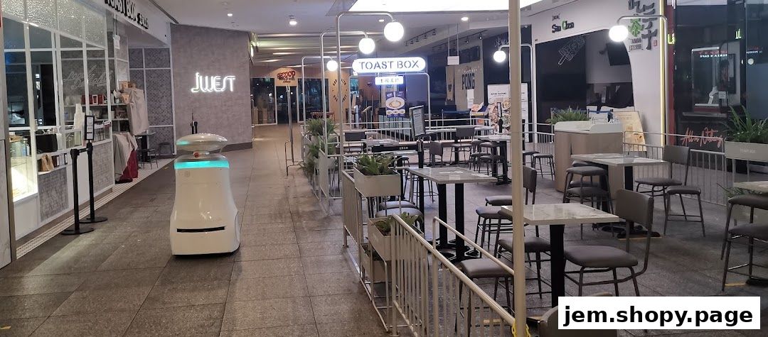 Exterior view of Toast Box JEM with outdoor seating and a service robot.