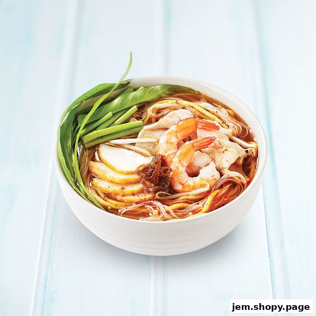A bowl of delicious noodle soup with shrimp, fish cake, and greens.