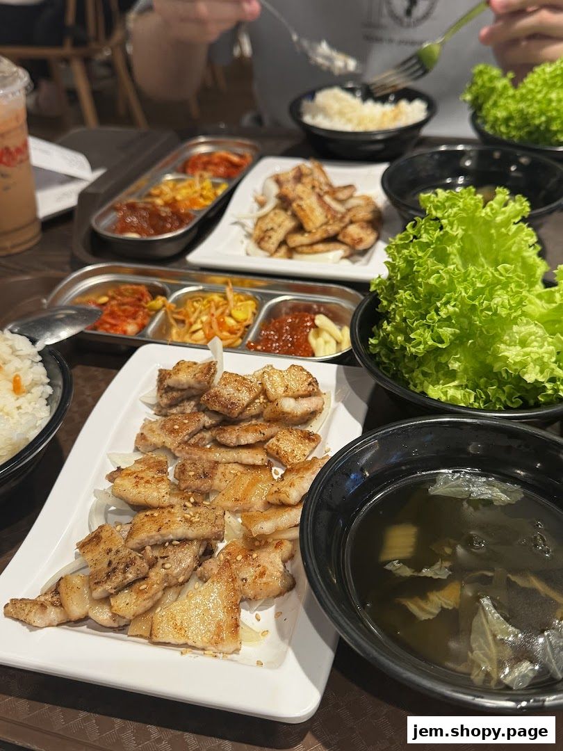 A table laden with Korean dishes, including grilled pork belly, kimchi, and rice.