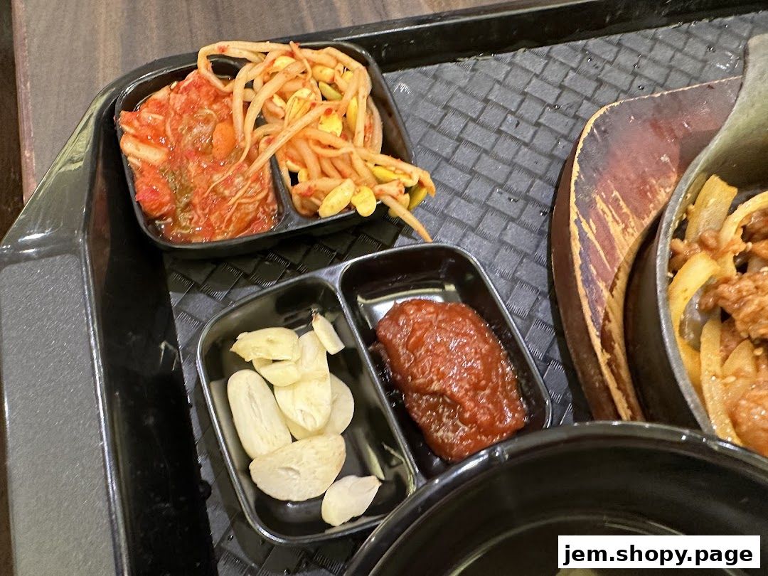 A tray of Korean side dishes including kimchi, bean sprouts, garlic, and gochujang.