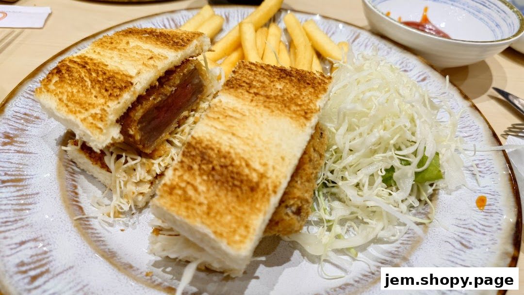 A delicious tonkatsu sandwich with fries and shredded cabbage on a plate.