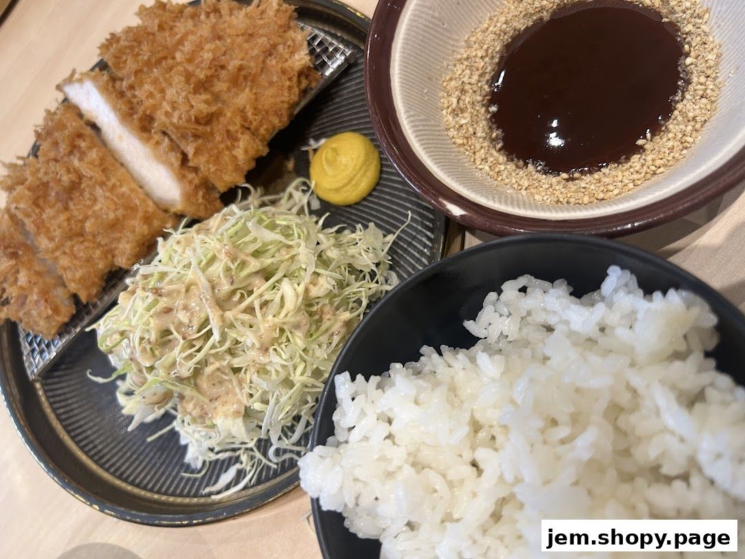 A delicious plate of tonkatsu, shredded cabbage salad, rice, and dipping sauce.