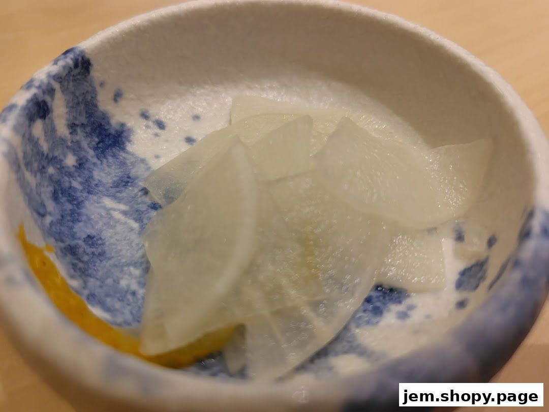 A close-up shot of thinly sliced pickled daikon radish in a decorative bowl.