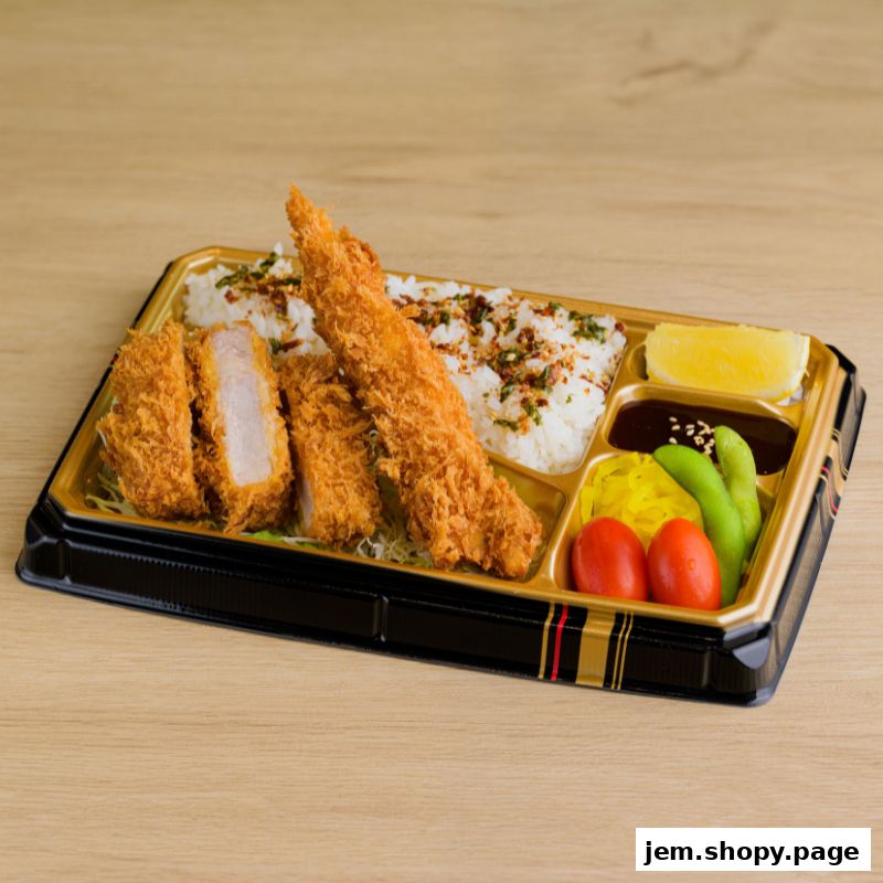 A bento box filled with crispy tonkatsu, a large fried shrimp, rice, and assorted side dishes.
