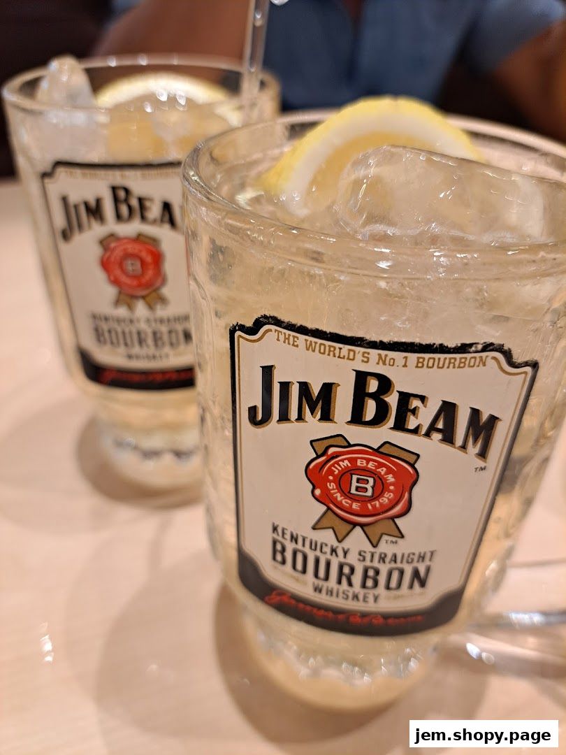 Two glasses of Jim Beam bourbon with ice and lemon slices.