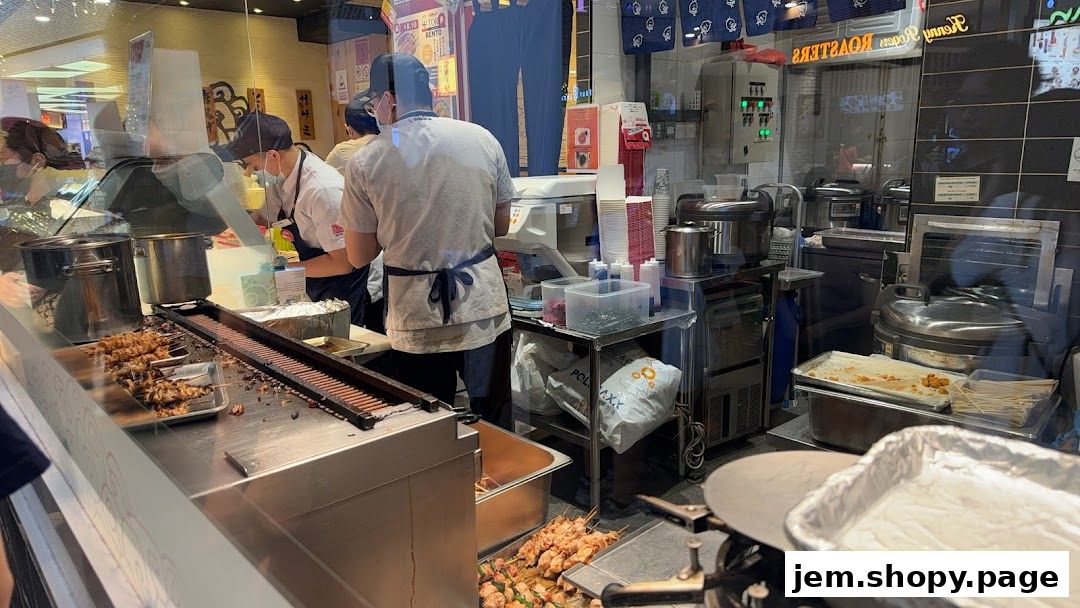 Chefs preparing skewers in a busy kitchen with various cooking equipment.