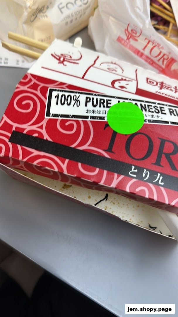 A close-up of a takeout box from TORI-Q JEM, featuring Japanese rice.