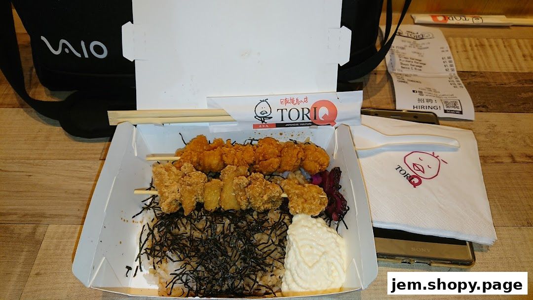 A bento box filled with Japanese yakitori skewers and rice, with a receipt and napkin.