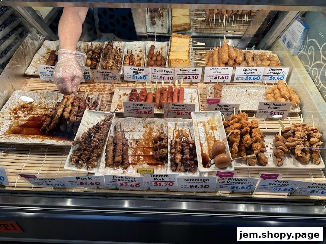 A display of various Japanese skewers and fried items with price labels.