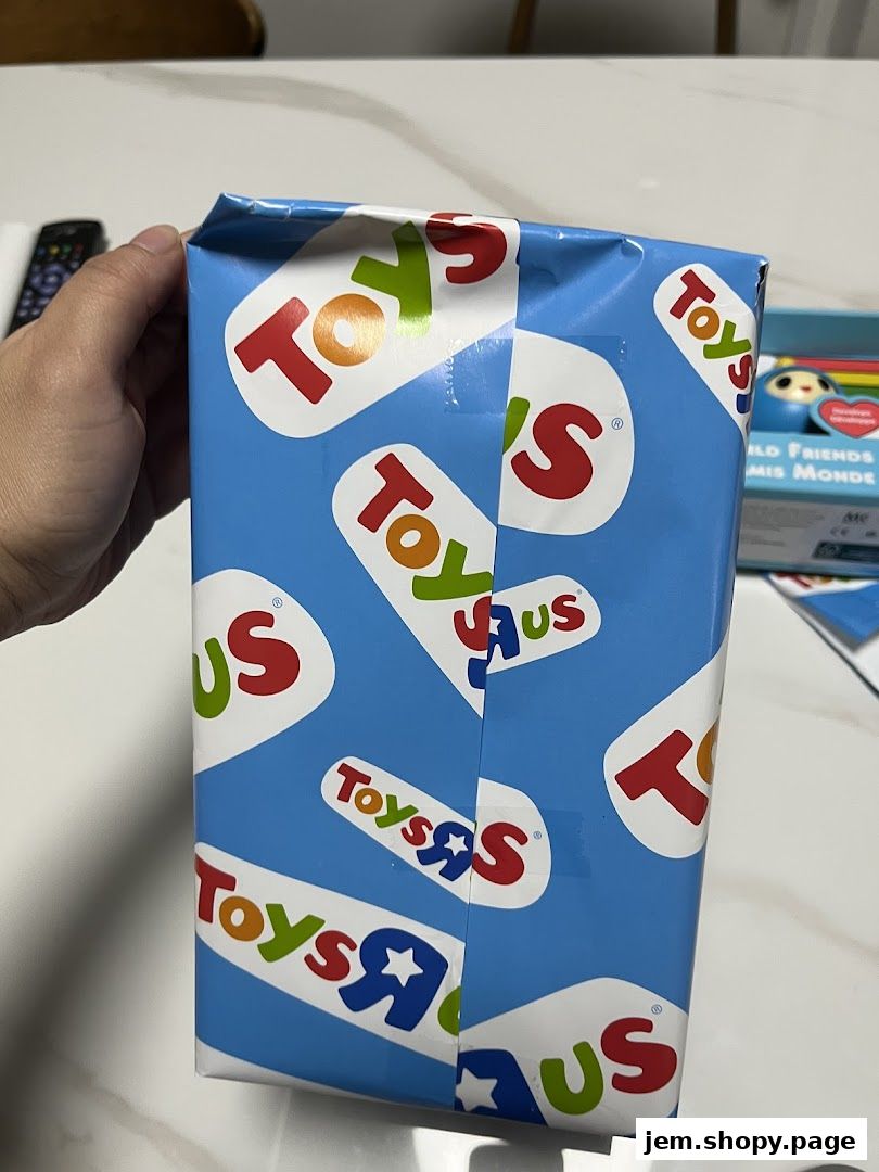 A hand holds a gift-wrapped box with the Toys R Us logo.