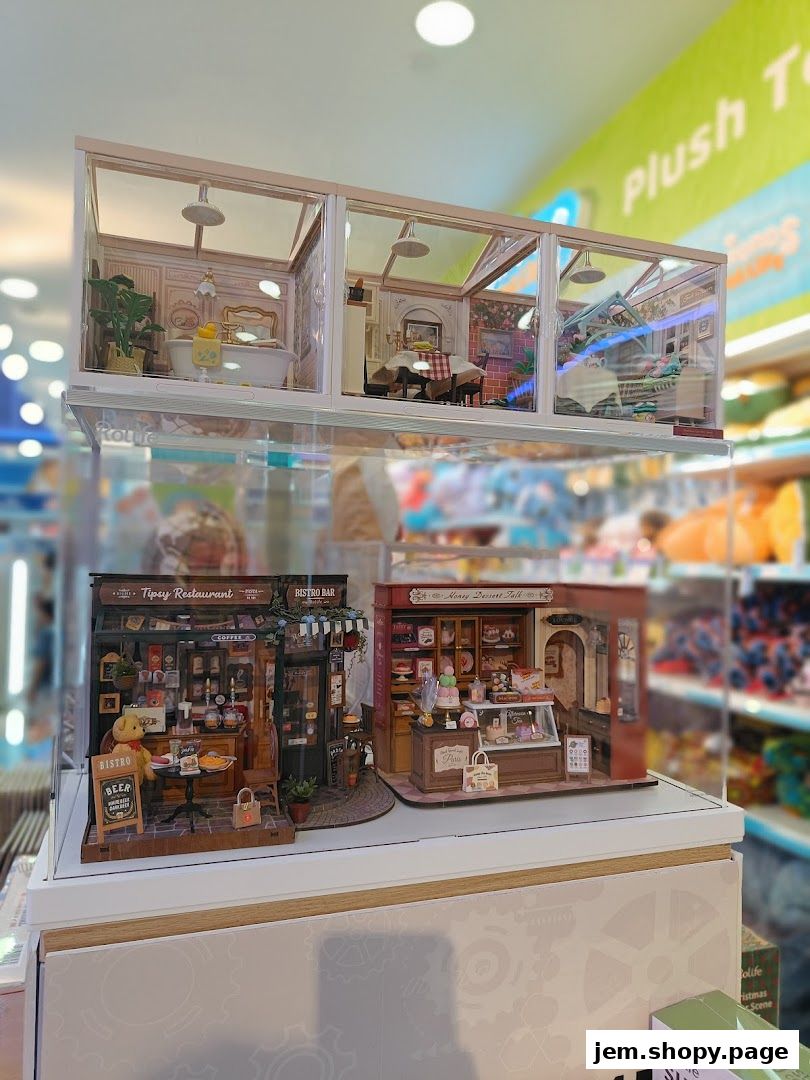 Miniature dollhouse scenes of a restaurant and dessert shop displayed in a retail store.