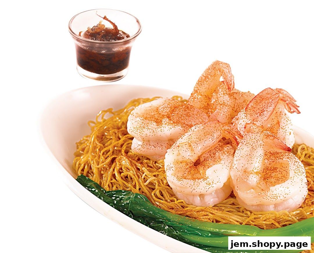 A close-up of a delicious shrimp noodle dish with a side of sauce.