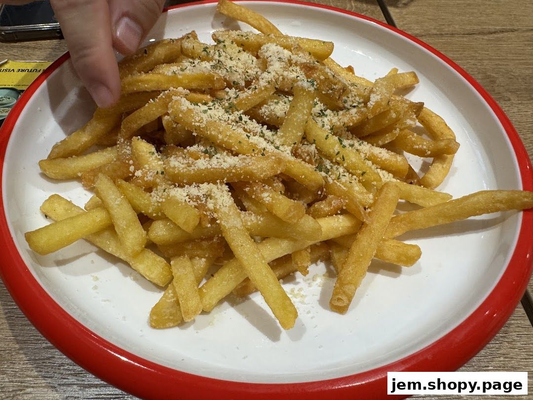 A plate of golden french fries topped with grated cheese and herbs.