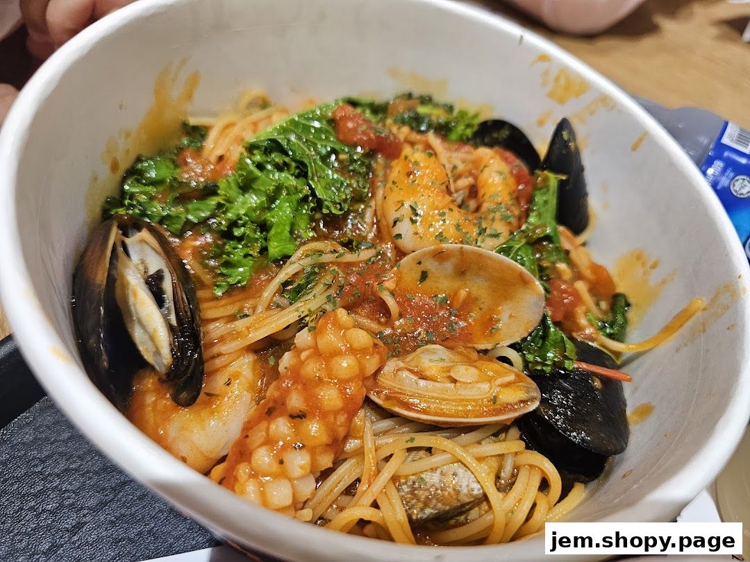A close-up shot of a delicious seafood pasta dish in a white bowl.