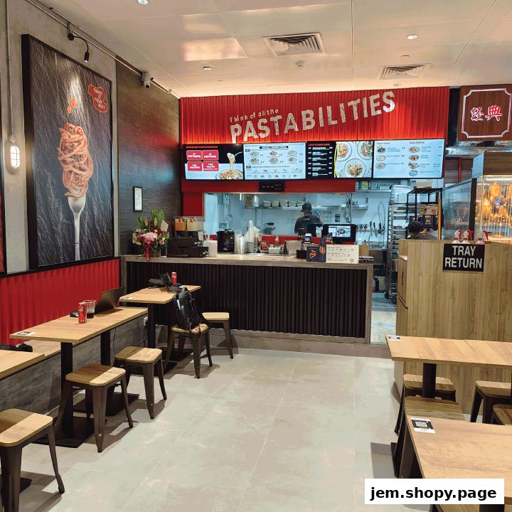 Interior of a pasta restaurant with tables, chairs, and a counter with digital menus.