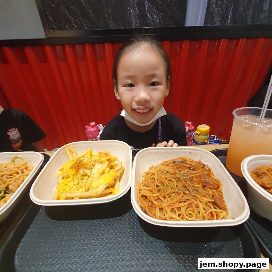 A young girl smiles at the camera with several dishes of food in front of her.