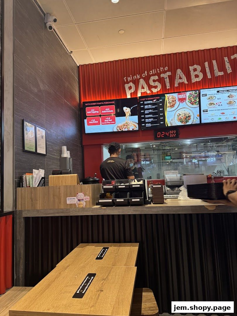 Interior view of a pasta shop with a digital menu board and seating area.